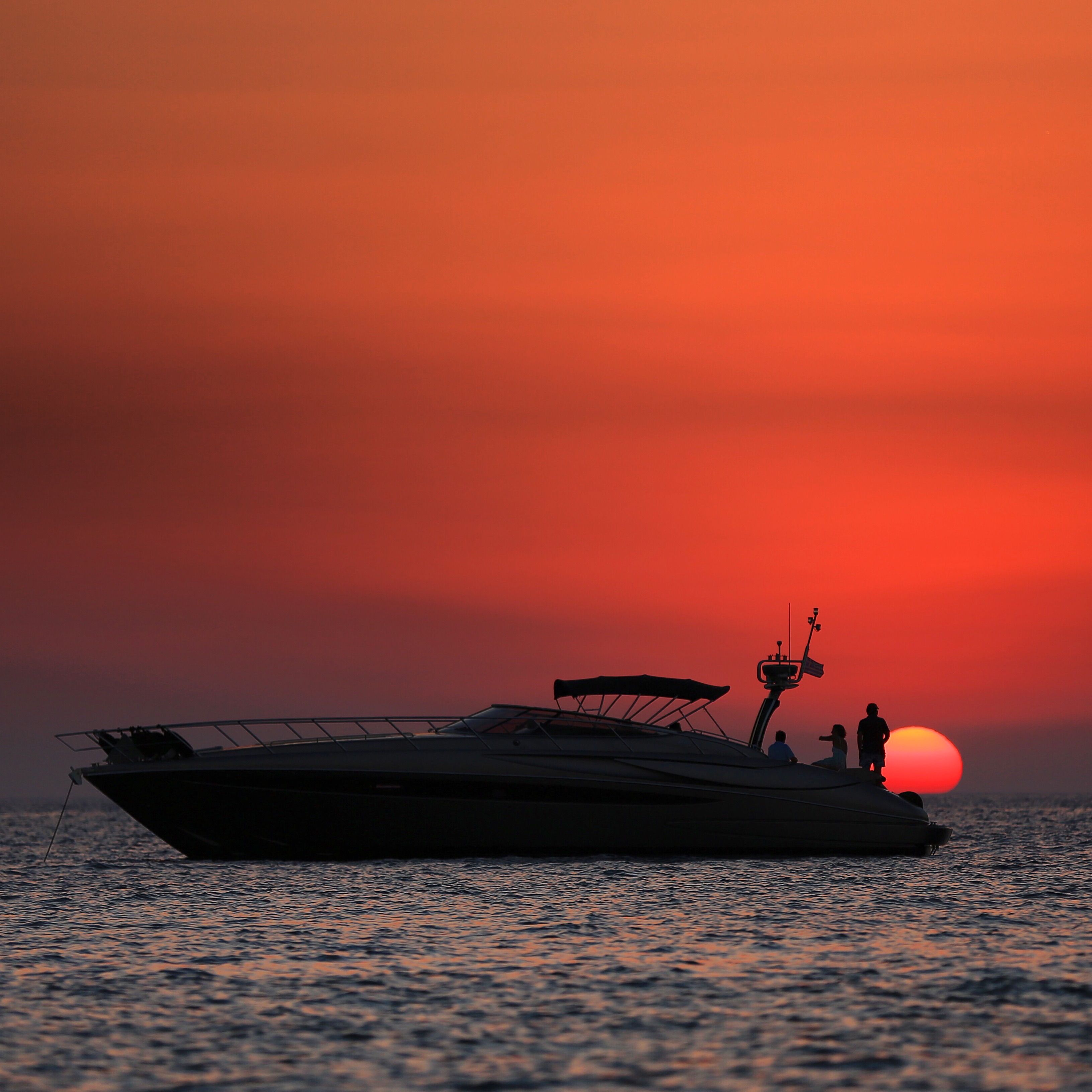 View from a yacht bow toward a calm sea at sunset