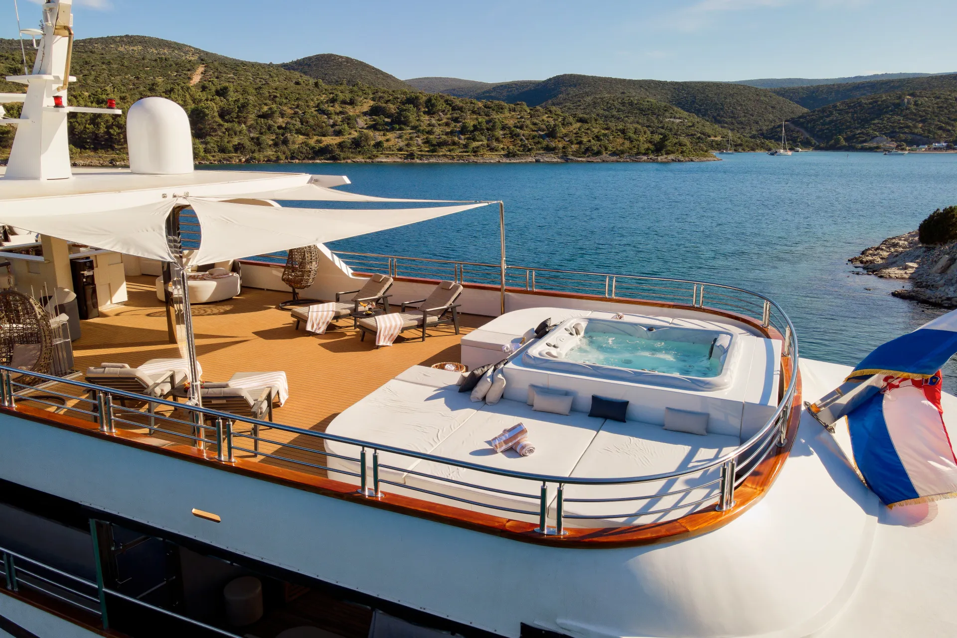 Luxury superyacht aft deck lounge overlooking a calm sea at golden sunset