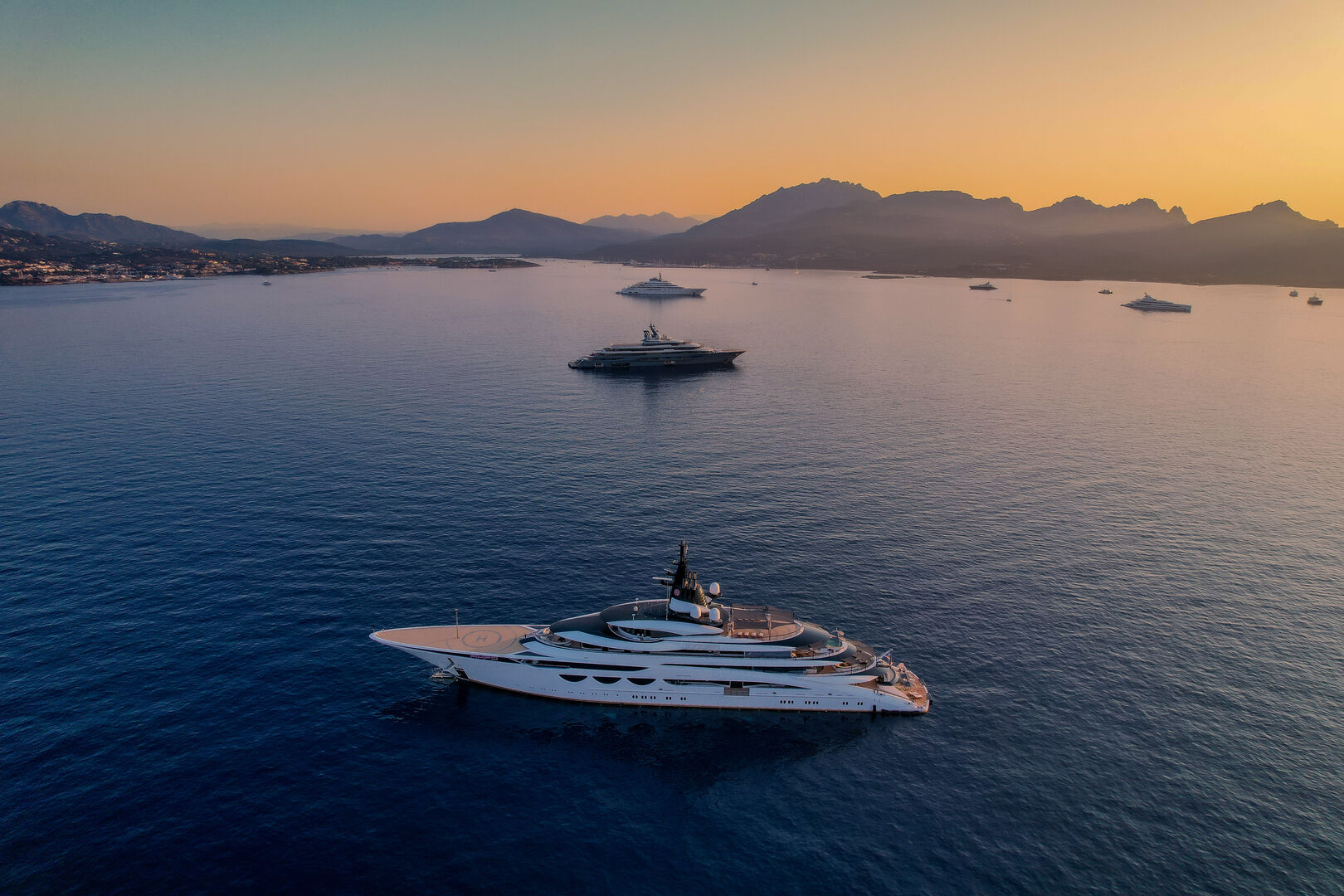 Superyacht cruising past a Mediterranean coastal town