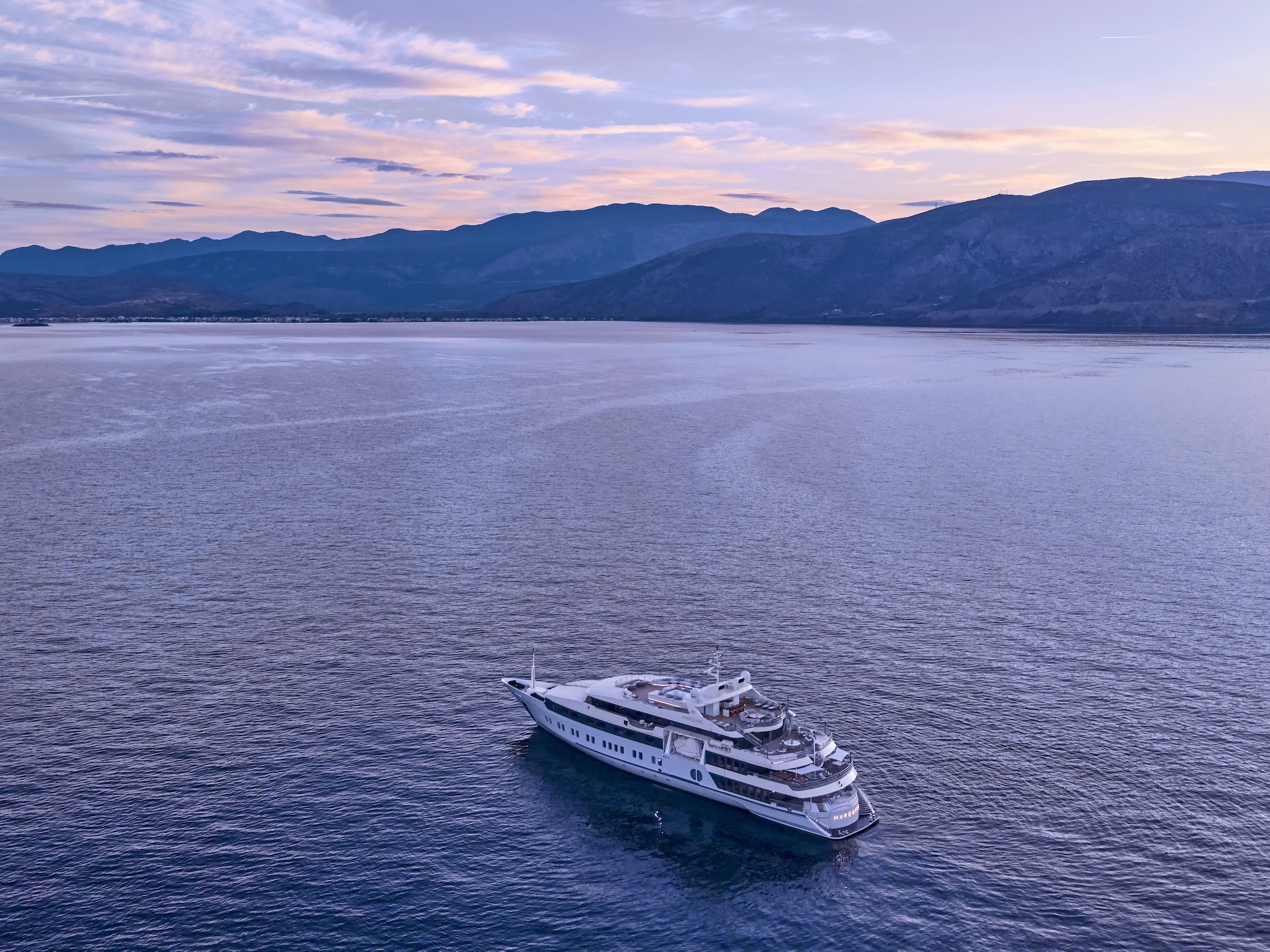 Superyacht cruising across calm water toward the sunset